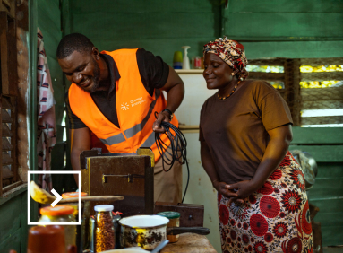 Un technicien d’Orange Énergies travaille dans la cuisine d’une africaine avec celle-ci qui observe