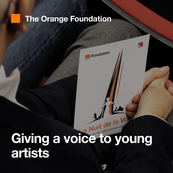 A person is seated at a concert organized by the Orange Foundation. 